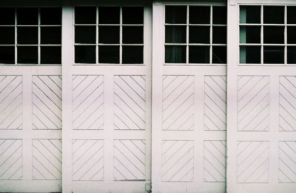 A photo of an older, wooden sliding garage door made of four panels, with windows near the top.